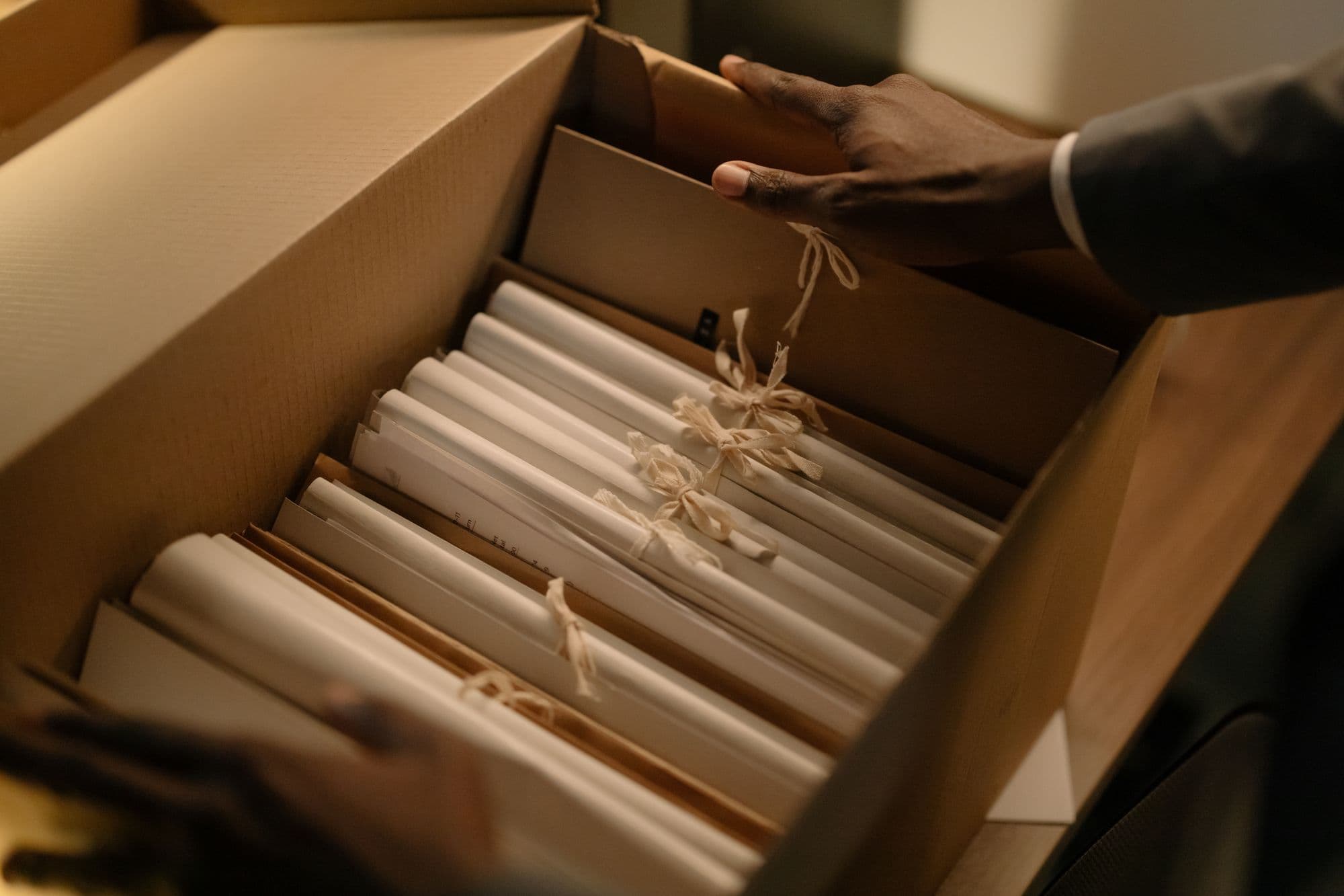 Hands opening a box of rolled papers tied with string