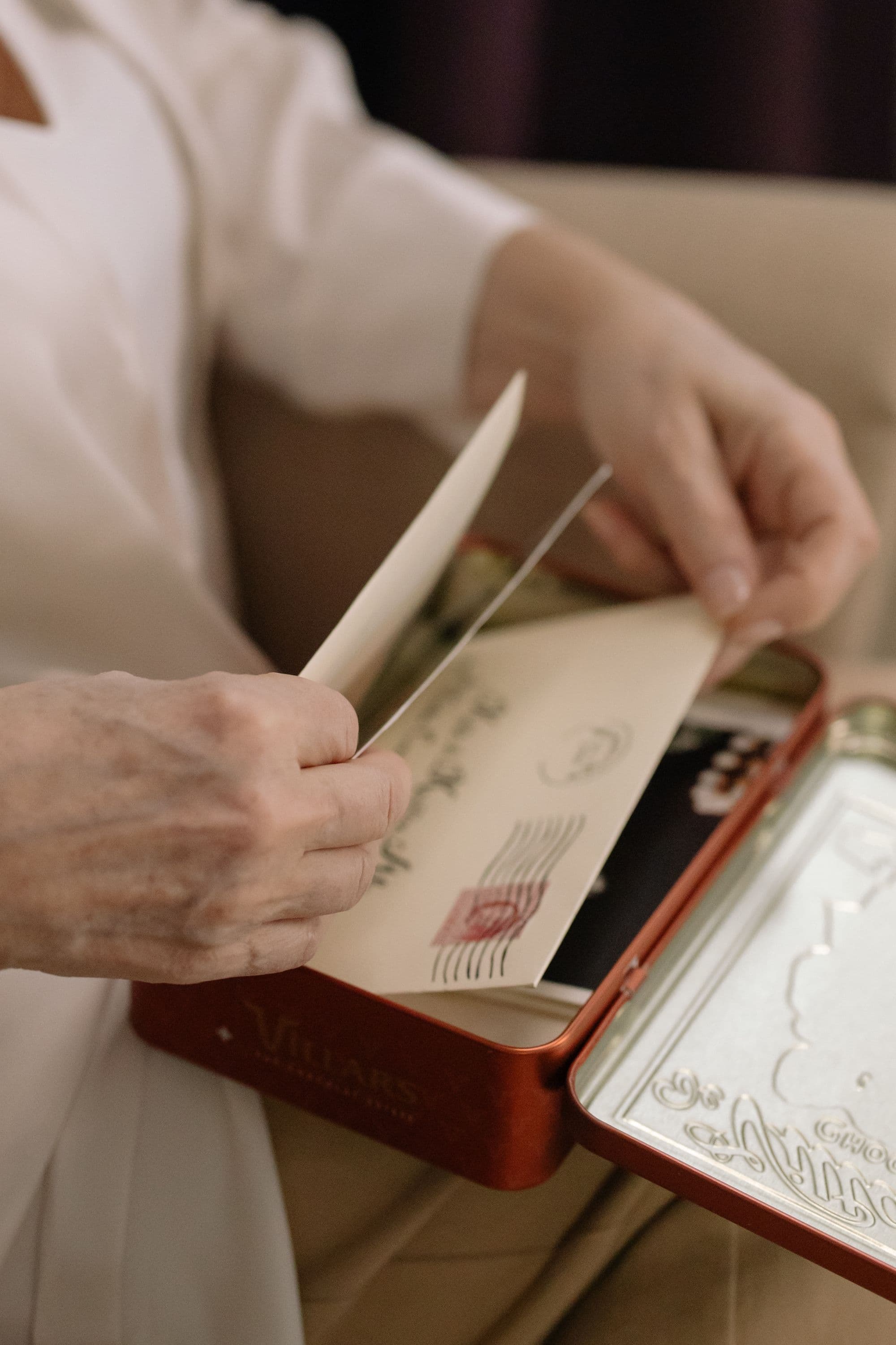 Older hands taking a letter from a keepsake tin