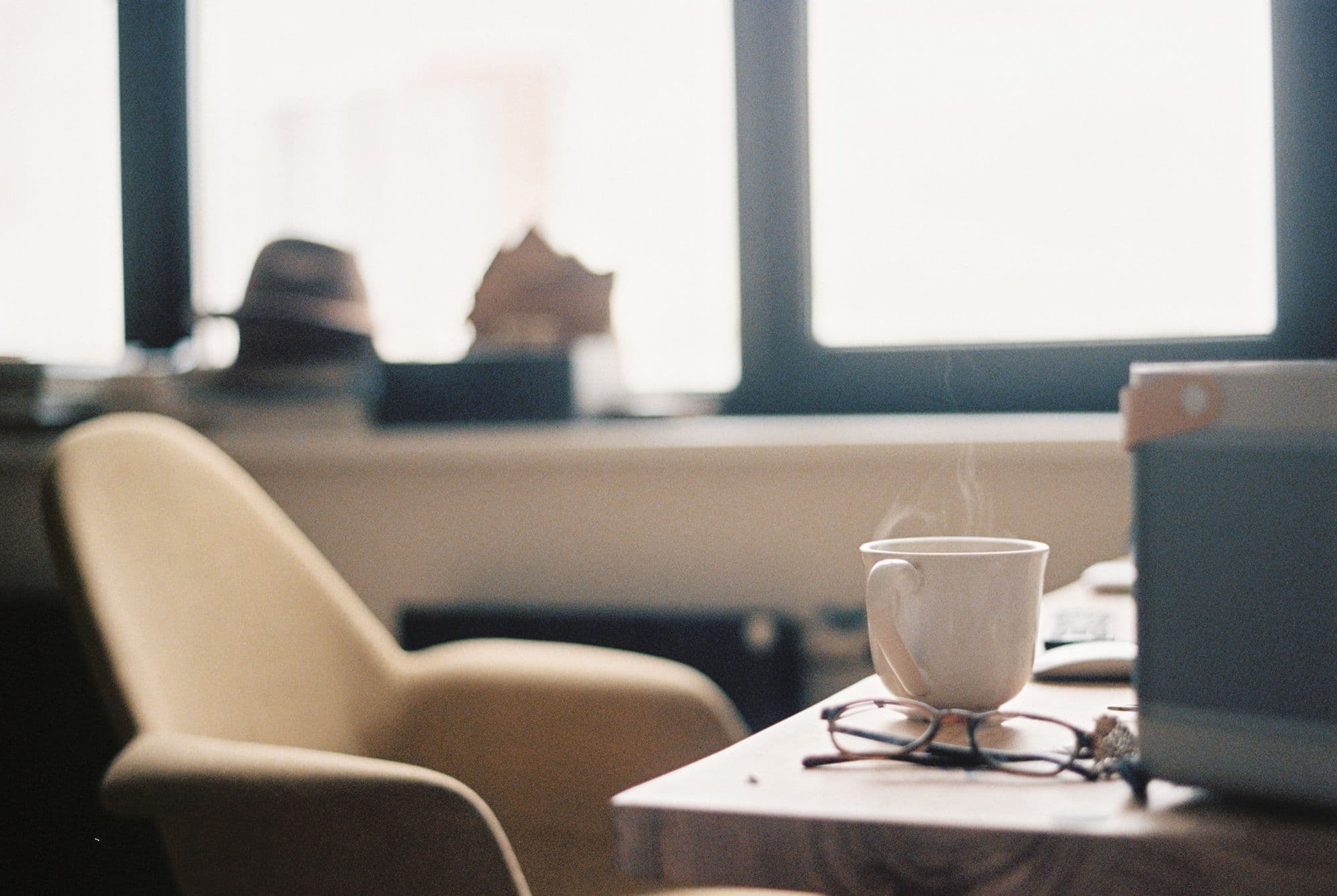 Morning light on a table with a cup of coffee and reading glasses